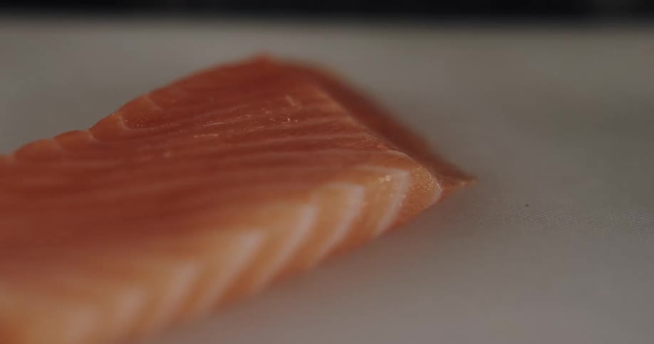 A person is cutting fish with a knife while wearing gloves