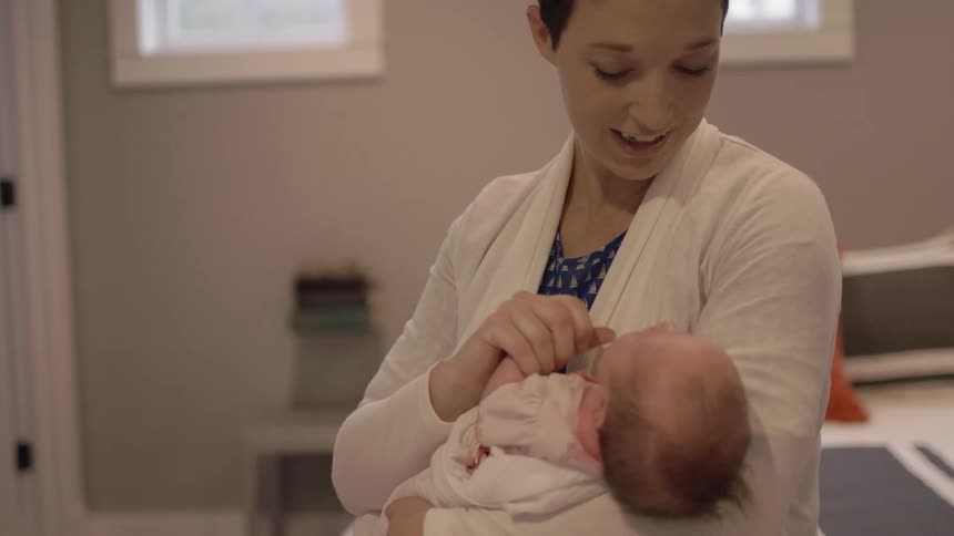 A woman is looking down at a baby in her arms