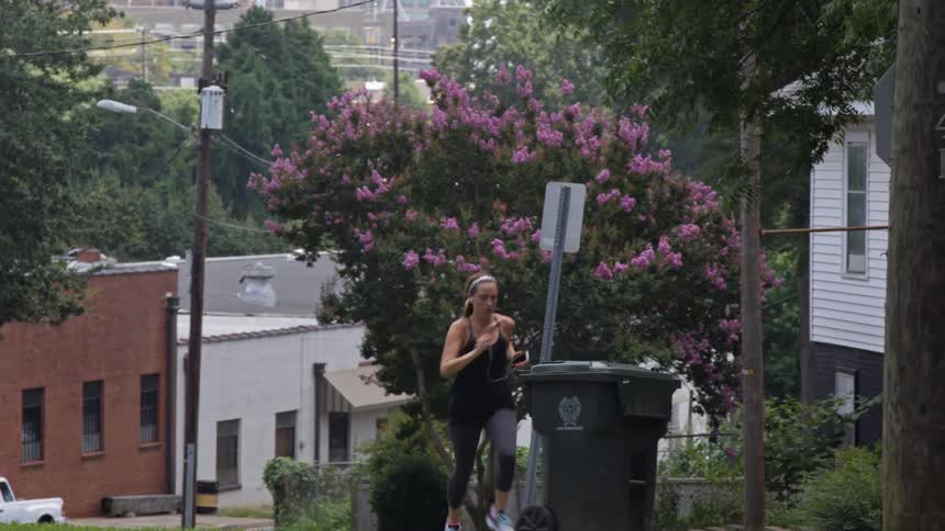 A woman is running uphill in a town