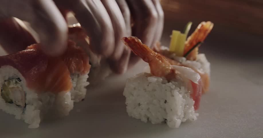 A person puts a mat over a sushi roll as they prepare it