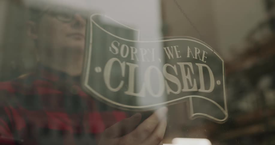 An employee flips a sign in the window to indicate that his business is open