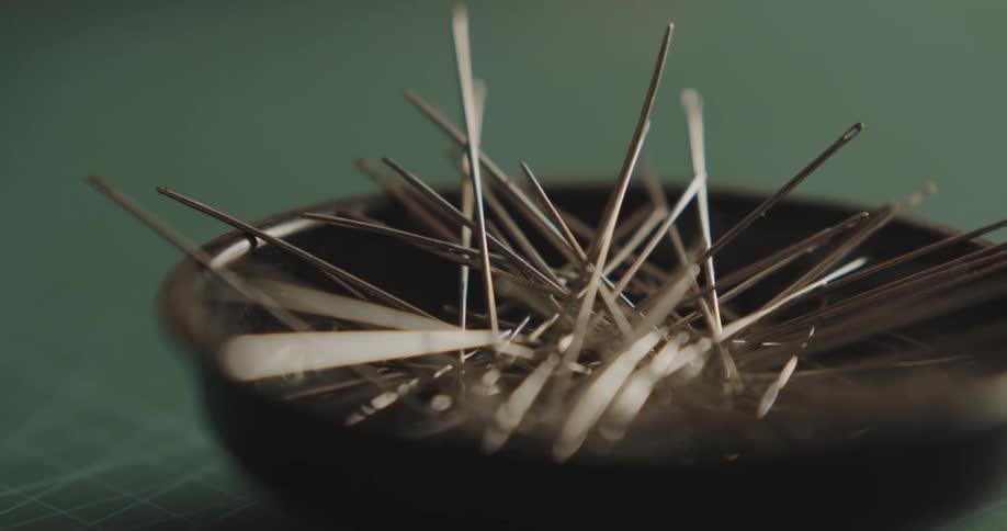 A person taking sewing needles from a bowl