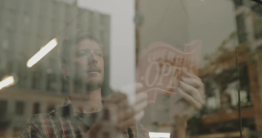 A business owner flips over the open sign for his business