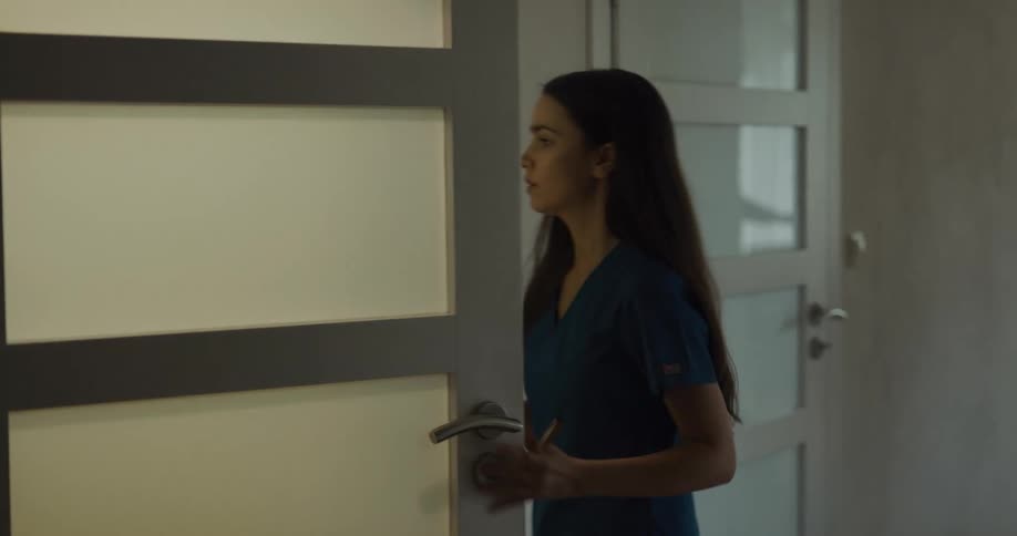 A young woman approaches and opens a door before entering