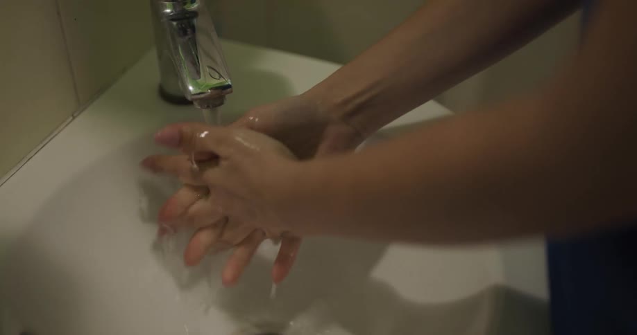 A person in a bathroom washing their hands in a sink