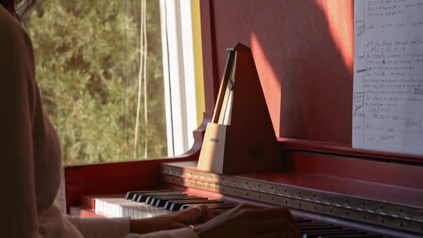 A person is playing the piano by a window
