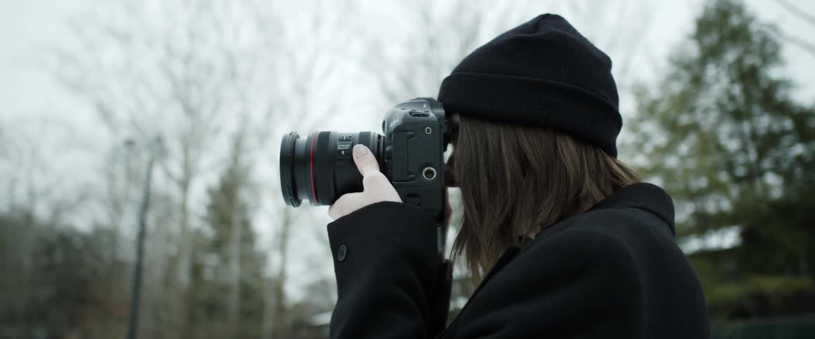 A woman is taking pictures outdoors with a camera