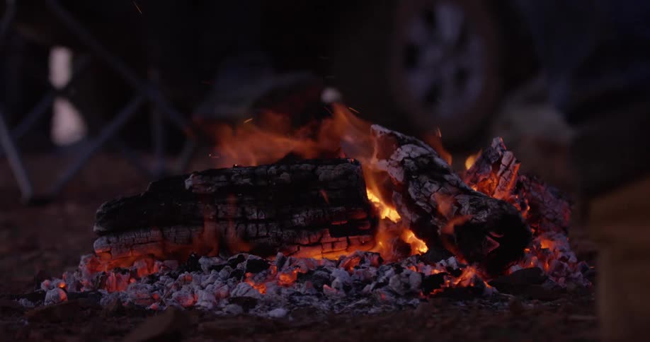 A person is walking by a bonfire at night