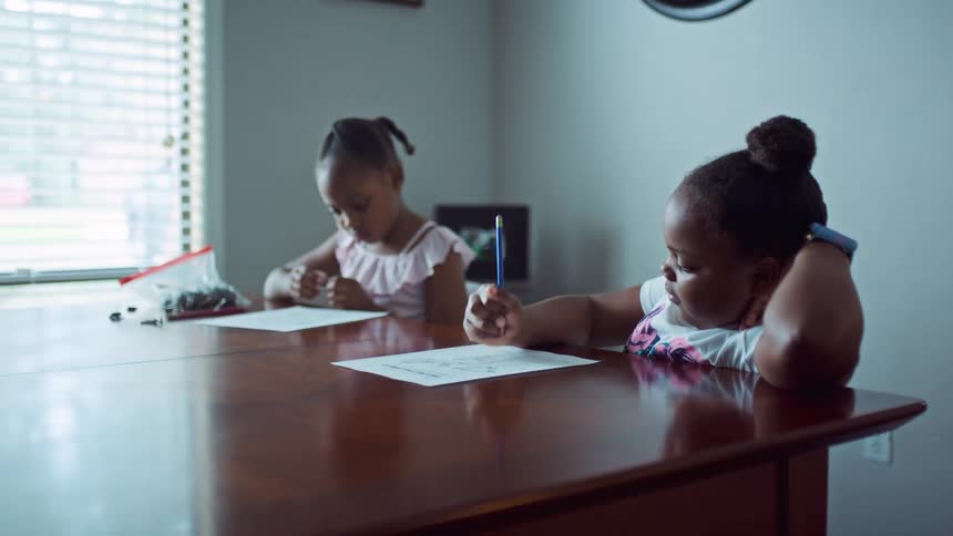 Two children writing on paper doing homework