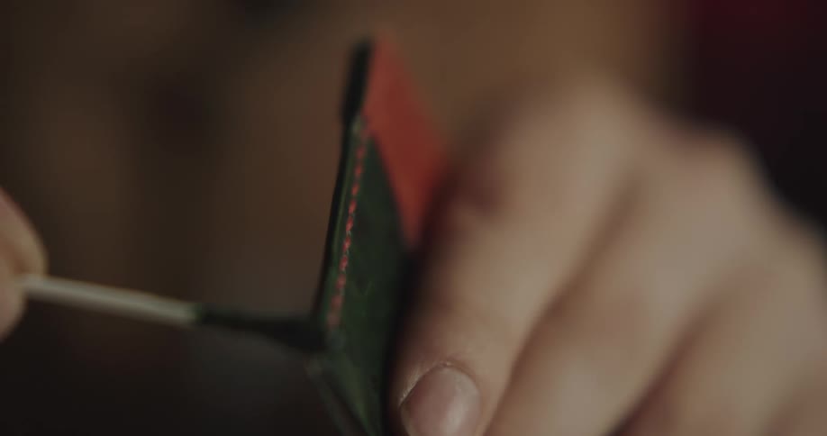 A person in a room adding black dye onto leather
