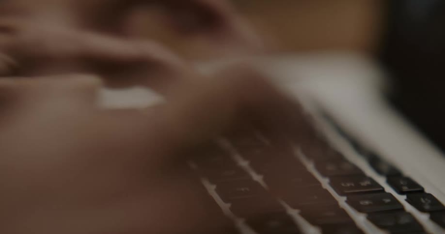 A person in a room typing on a laptop