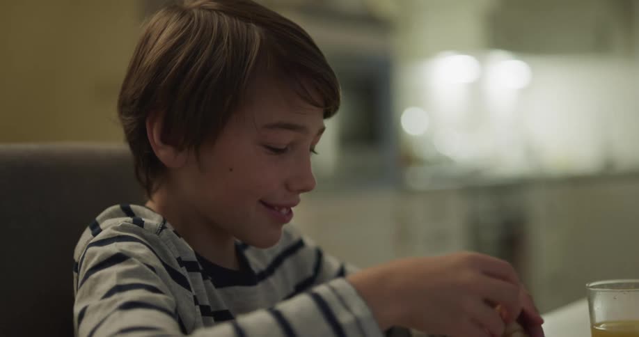 Boy sits at dining table eating with family