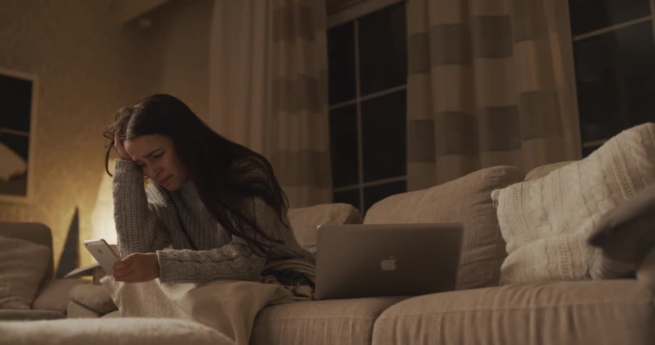 A woman in pain looking at a phone