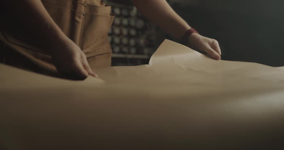 A person in a workshop putting down construction paper on a table