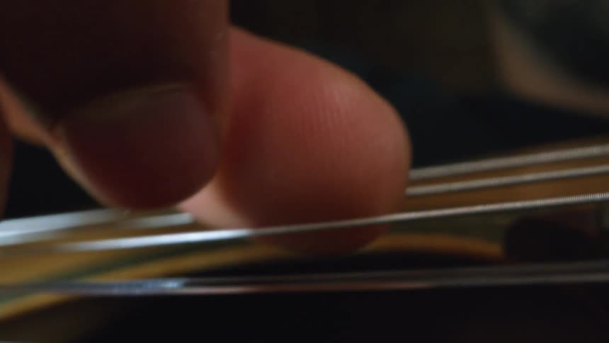 Mans fingers playing a string instrument