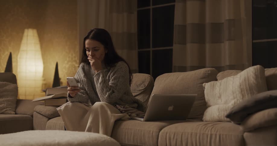 A woman puts down her laptop to pick up her phone