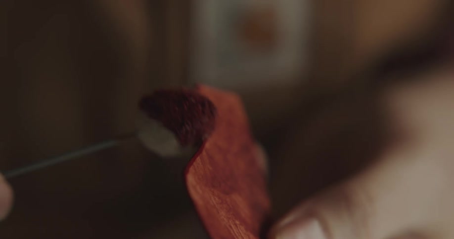 A person in a room adding red dye onto leather