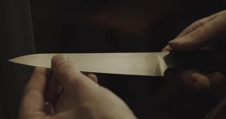Mans hands hold a sharp knife