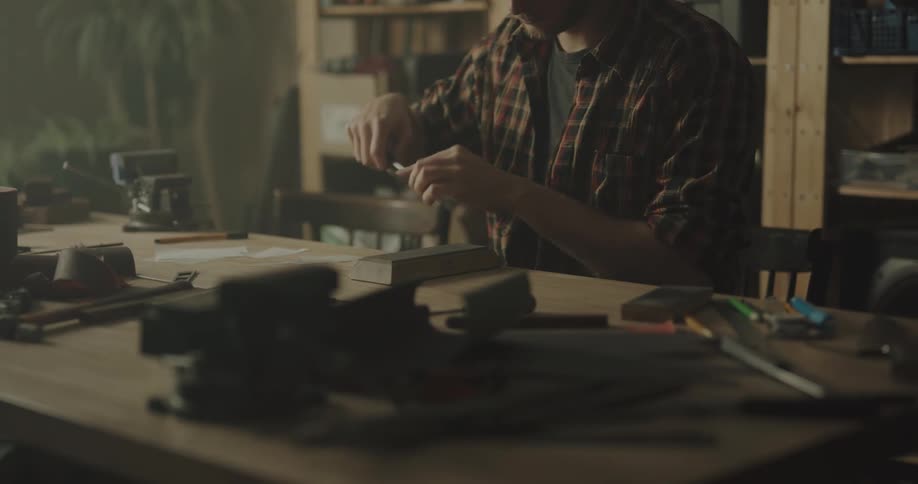 A man is sitting indoors and doing crafts