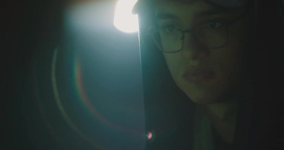 A man in a room with a hat glasses and a hoodie