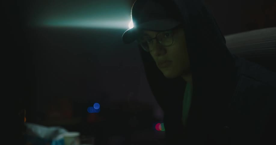 Teenager boy sitting in front of a computer screen and typing with snacks at his side