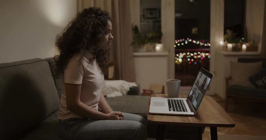 Woman sits on a sofa and participates in a video chat on a laptop