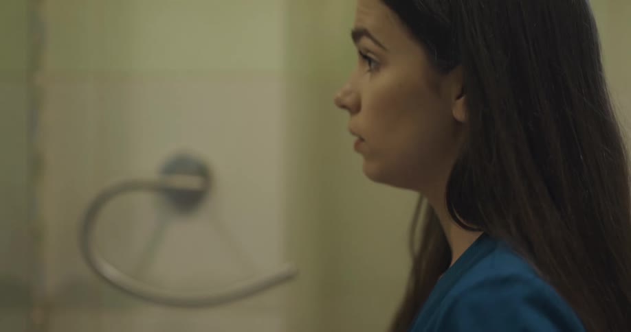 A woman putting on makeup in a bathroom mirror