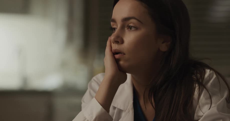 A doctor sits down and removes her mask