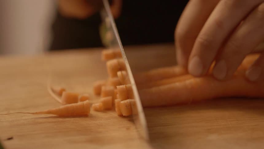 A person chops carrots into small pieces
