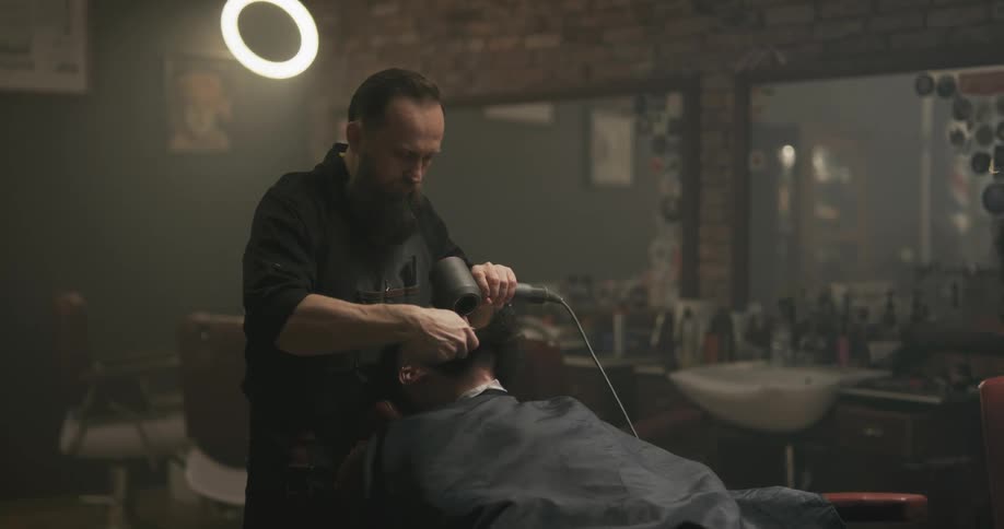 A barber combs and dries a clients beard