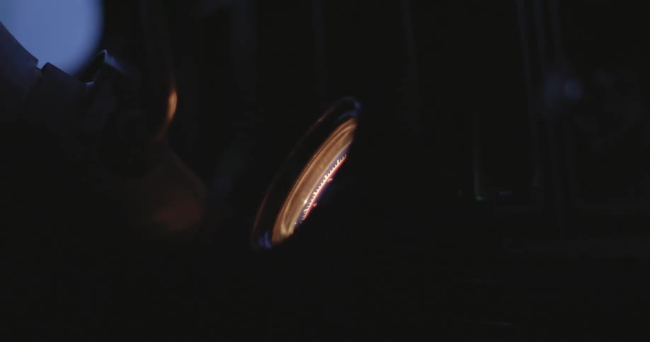 A man uses a small lamp to light up a dark room near tools