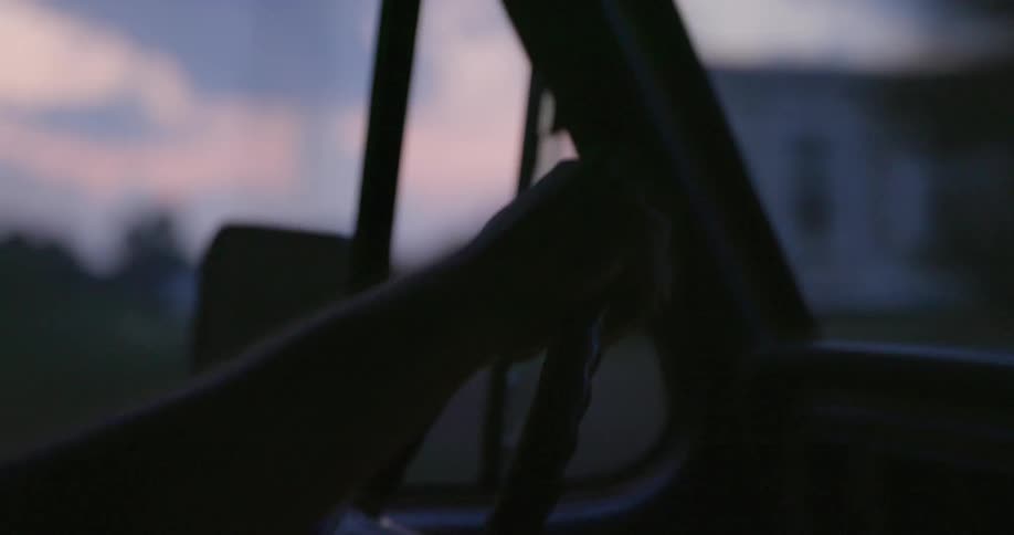 A person drives a vehicle down a road on a cloudy evening