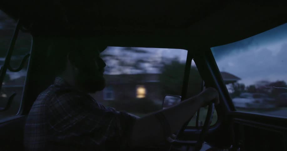 White man driving his car at dusk