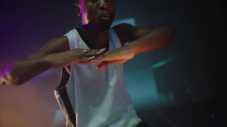 A dancer dances on a stage with projected photos and flashing lights in the background