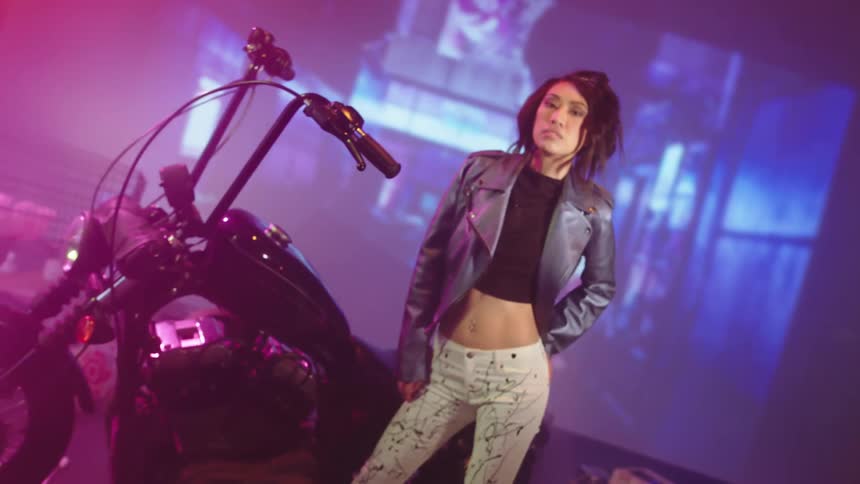 A woman poses in front of a motorcycle