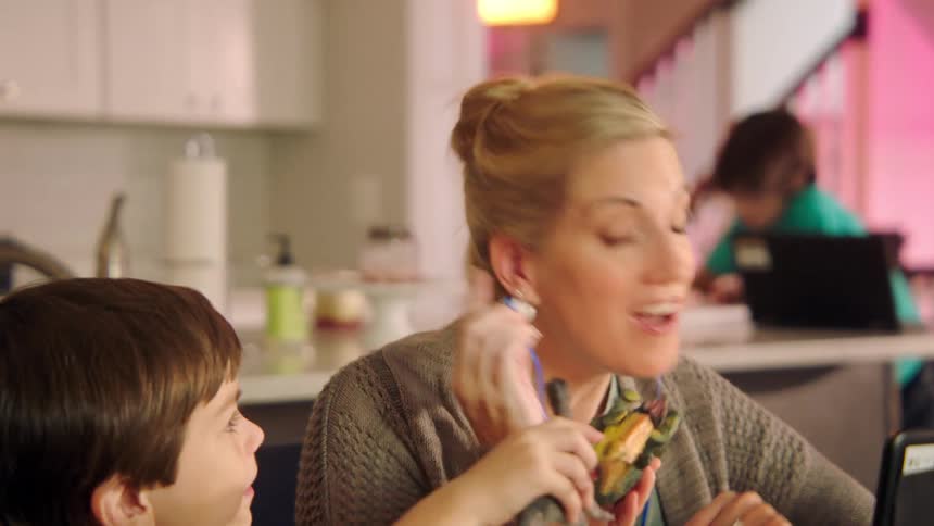 A female takes out her earbuds as a young boy is distracting her with a toy