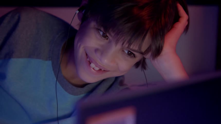 A child talking to someone on a laptop and laughing