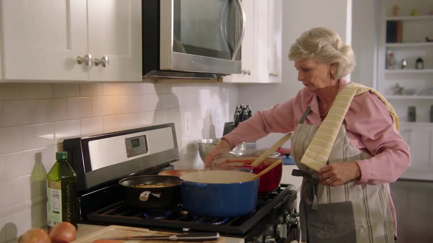 A woman cooking on a stove with large pots
