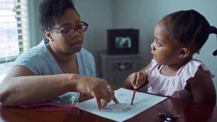 Black female teacher instructs a young student while the student pokes the teachers nose with a pencil