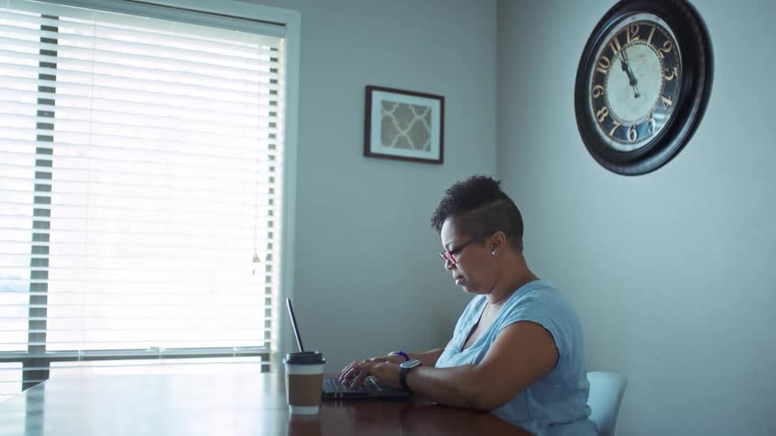 Woman sitting at the table typing on her laptop