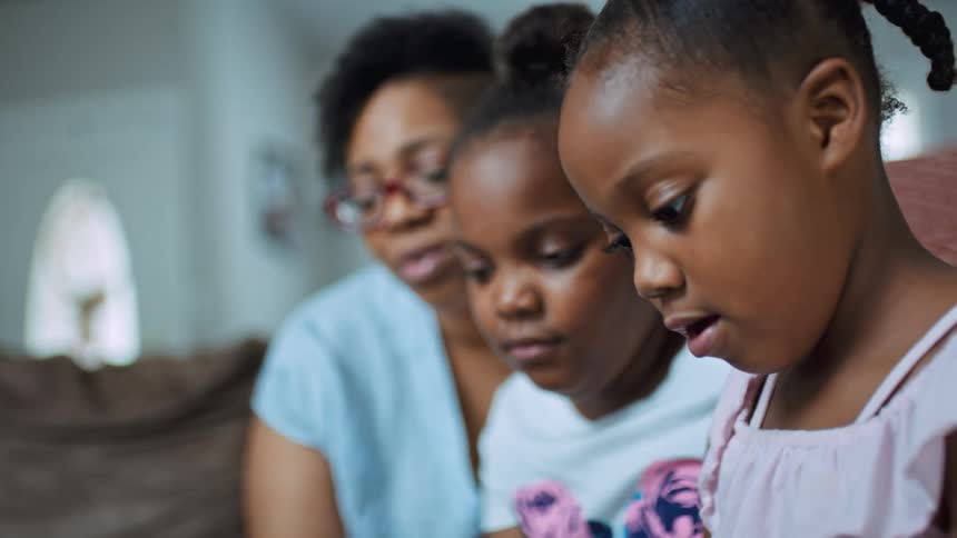 A woman and two girls sitting on a couch with a wall and a door in the background