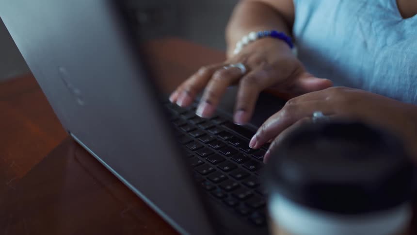 Black woman typing on her laptop while sitting at a table