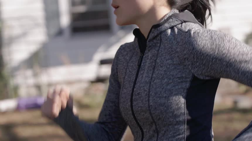 A woman is running down a street past cars