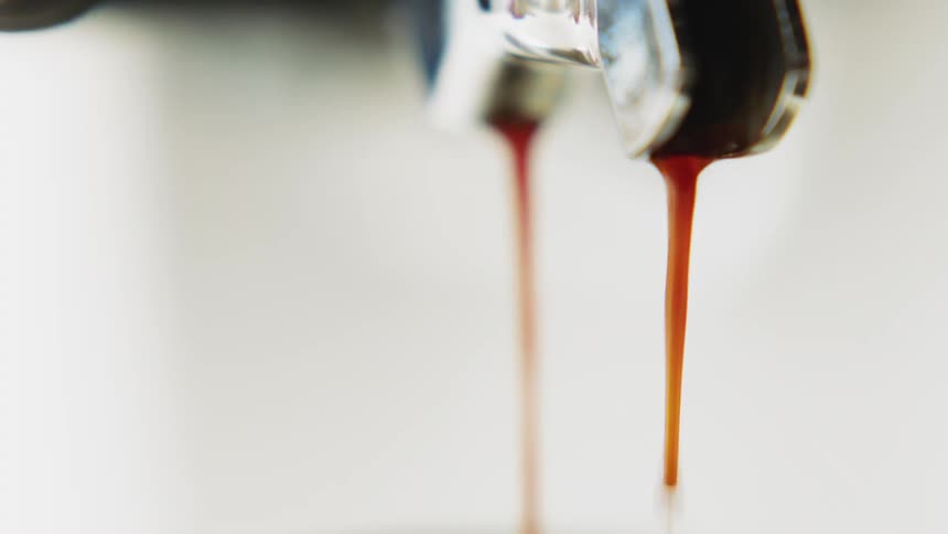 Coffee pours from a spout into a cup