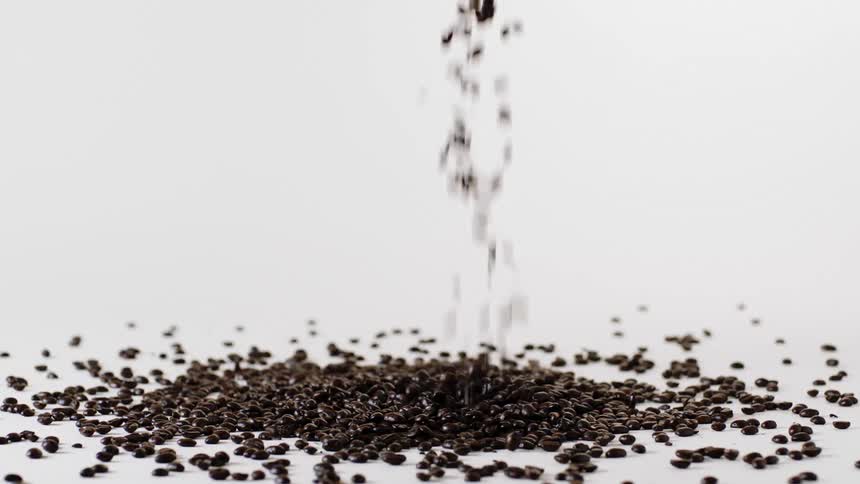 Coffee beans falling into a pile and bouncing around on a white table