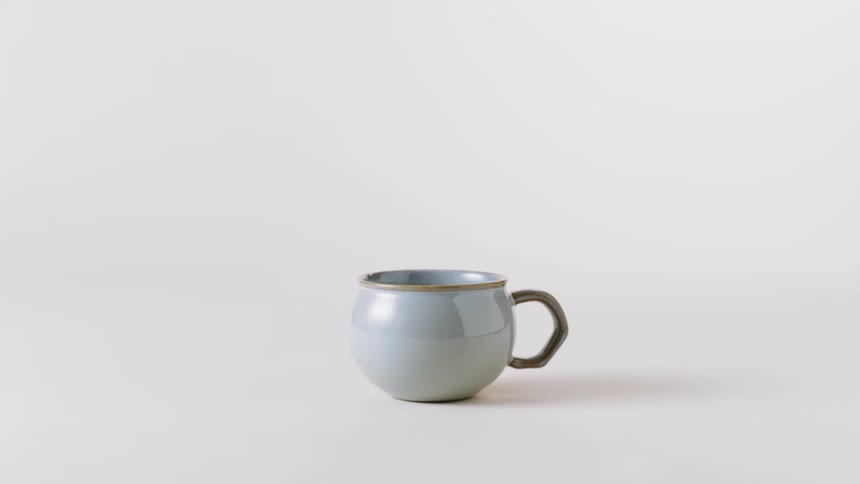 A round coffee mug with interesting handle against a white background