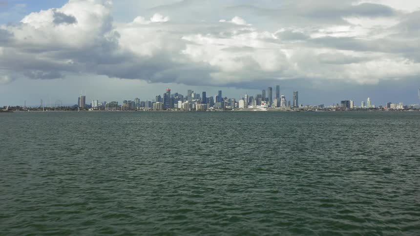 A city skyline is visible across a vast ocean
