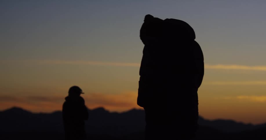 Two people stand outside at sunset