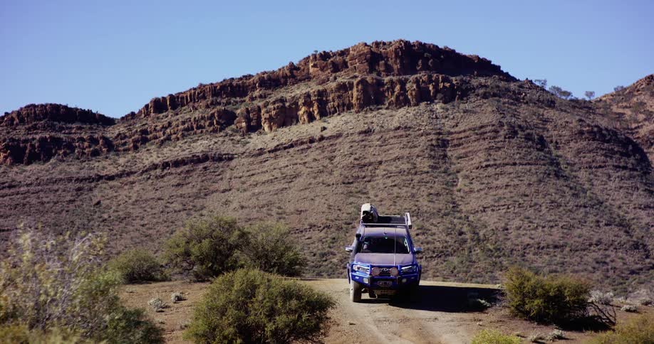 A vehicle driving at the base of a cliff