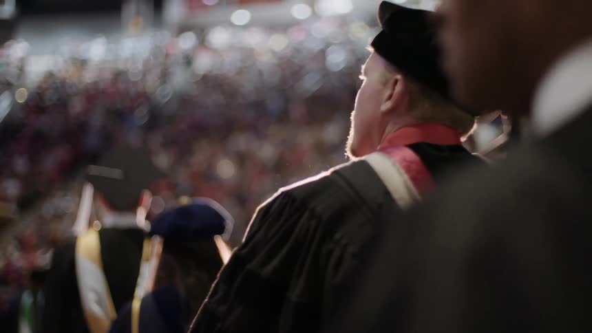 A group of graduates walk forward in line